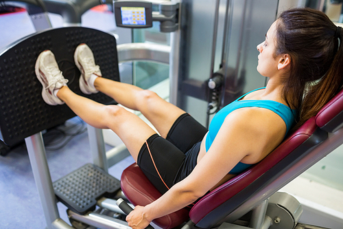 Focused woman doing leg training at the gym