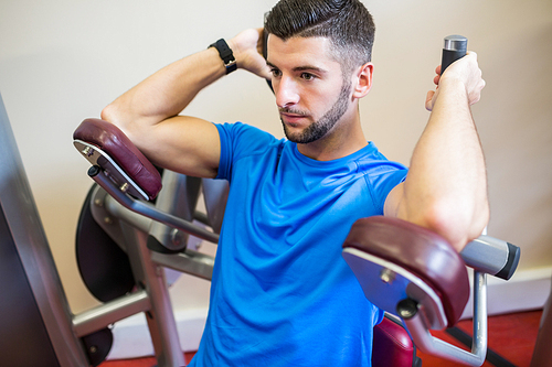 Concentrating man using weights machine at the gym