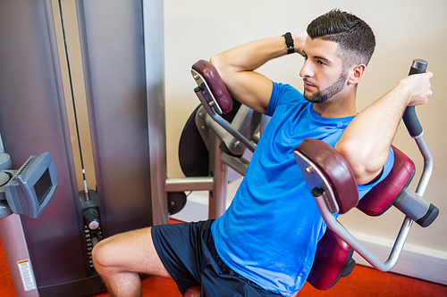 Concentrating man using weights machine at the gym