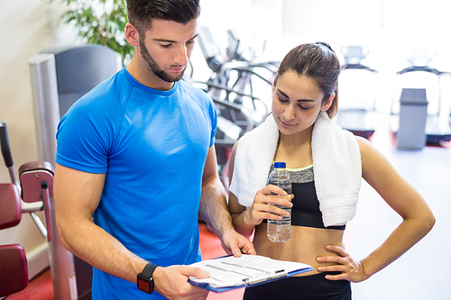 Trainer and athlete discussing workout plan at the gym