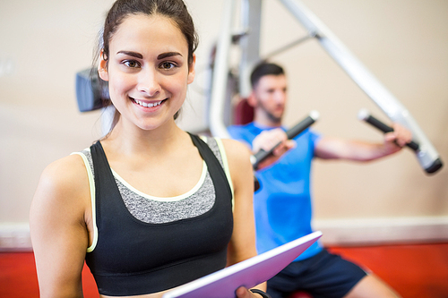 Trainer working with athlete at weights machine at the gym