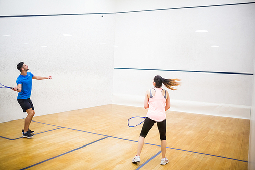 Competitive couple playing squash in the squash court