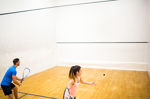 Competitive couple playing squash together in the squash court