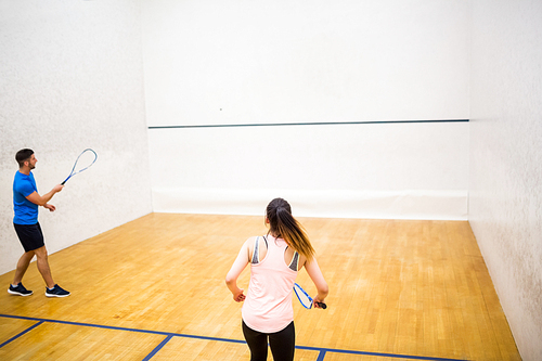 Competitive couple playing squash together in the squash court