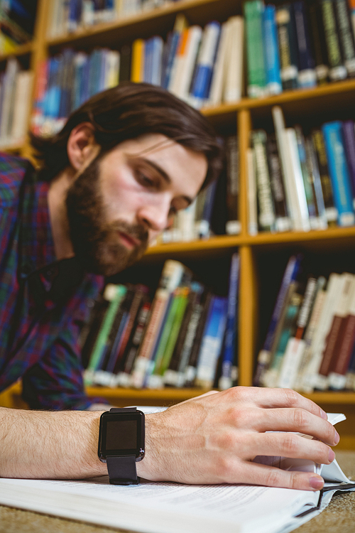 Student studying on floor in library wearing smart watch at the university