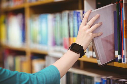 Students hand with smartwatch picking book from bookshelf at the university