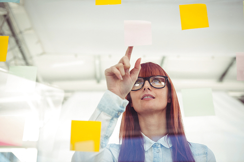 Attractive hipster woman pointing sticky notes in her office