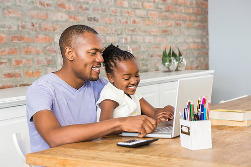 Cute daughter using laptop at desk with father in living room