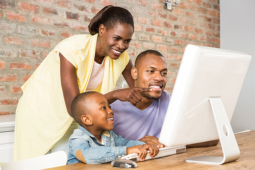 Casual smiling family on a computer in living room