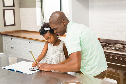 Father helping his daughter with homework in the kitchen