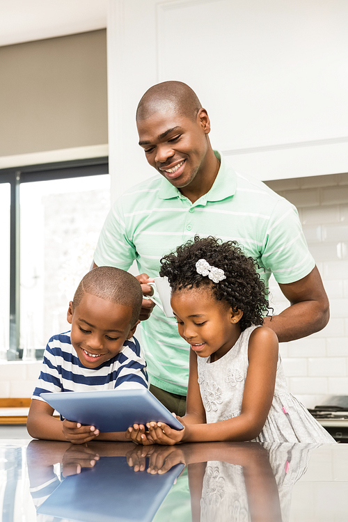 Father using tablet with his children in kitchen at home