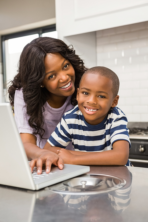Mother and son using laptop in the kitchen