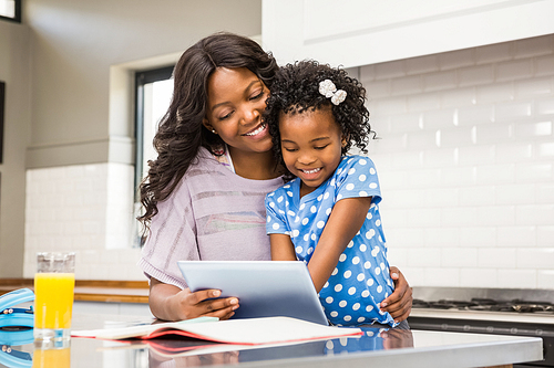 Mother and daughter using tablet in the kitchen