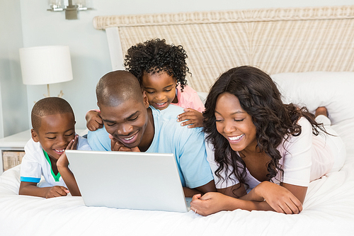 Family having fun together in bed with laptop
