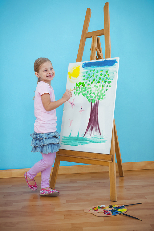 Smiling girl beside her picture on an easel