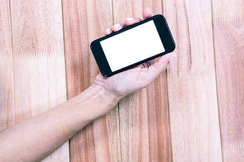 Part of hand typing on smartphone on wooden desk