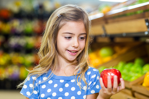 Cure girl holding an apple in the grocery