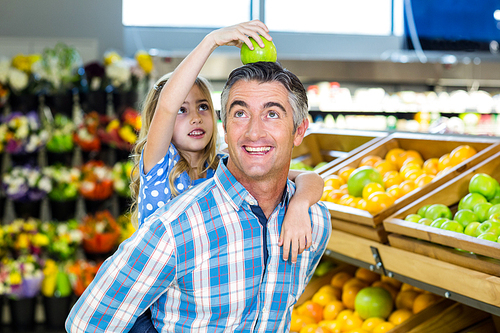 Father giving his daughter a piggy back at supermarket