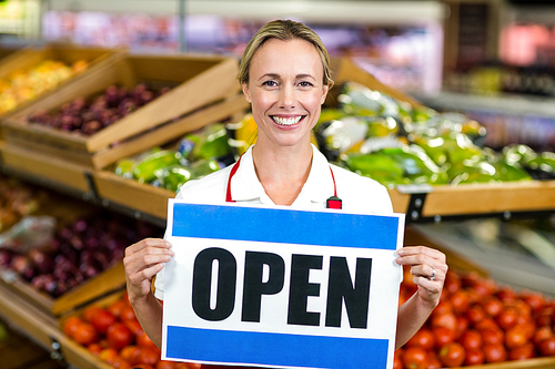 Smiling woman holding sign at supermarket