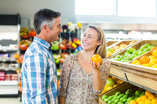 Happy smiling couple picking orange at supermarket