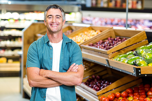 Portrait of a smiling man with arms crossed at supermarket