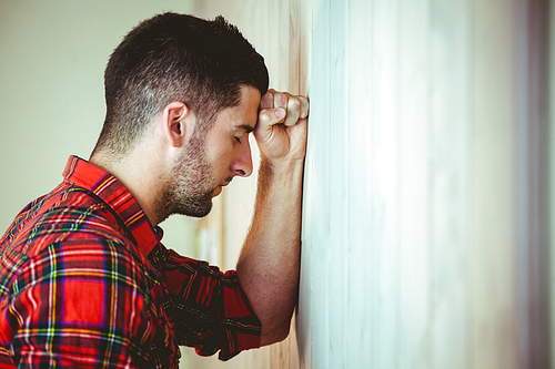 Handsome hipster feeling stressed out on wooden background