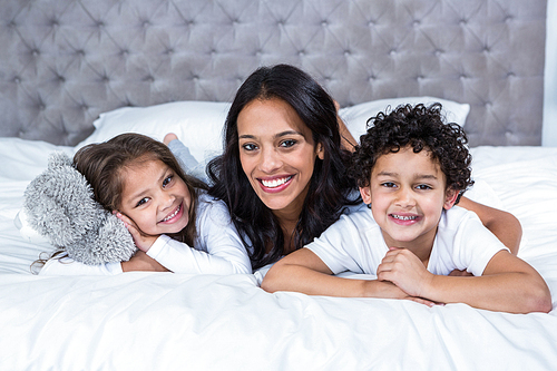 Portrait of smiling mother with children on the bed