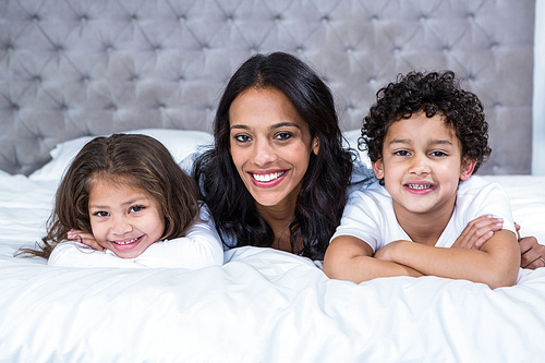 Smiling mother with children on the bed at home
