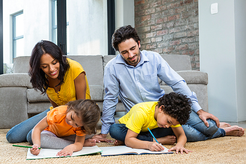 Family sitting on carpet in living room with children drawing