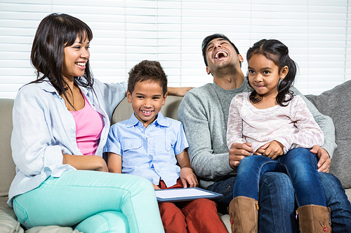 Smiling family using tablet on the sofa in living room