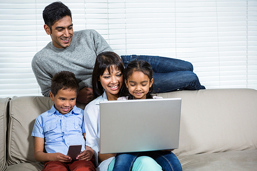 Smiling family using laptop on the sofa in living room