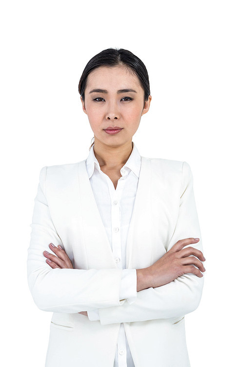 Serious businesswoman with crossed arms against white background