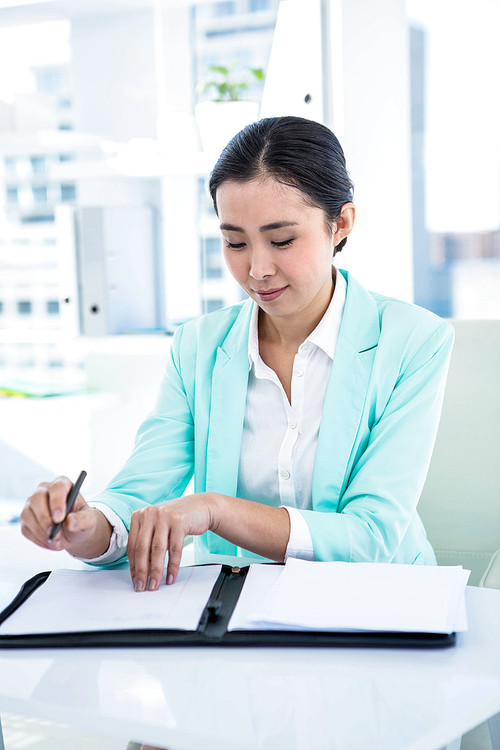 Smiling businesswoman with notes at desk in work