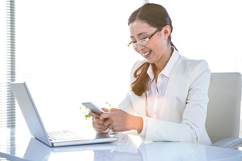 Smiling business woman using smartphone in her office