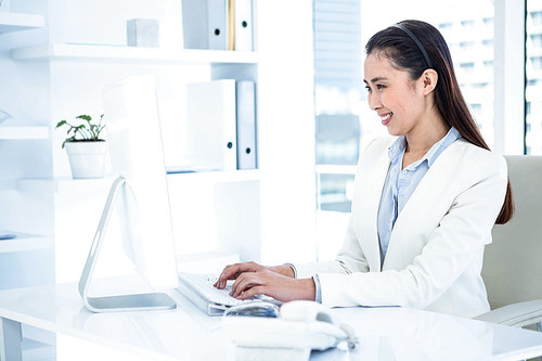 Smiling businesswoman using laptop at the desk in work