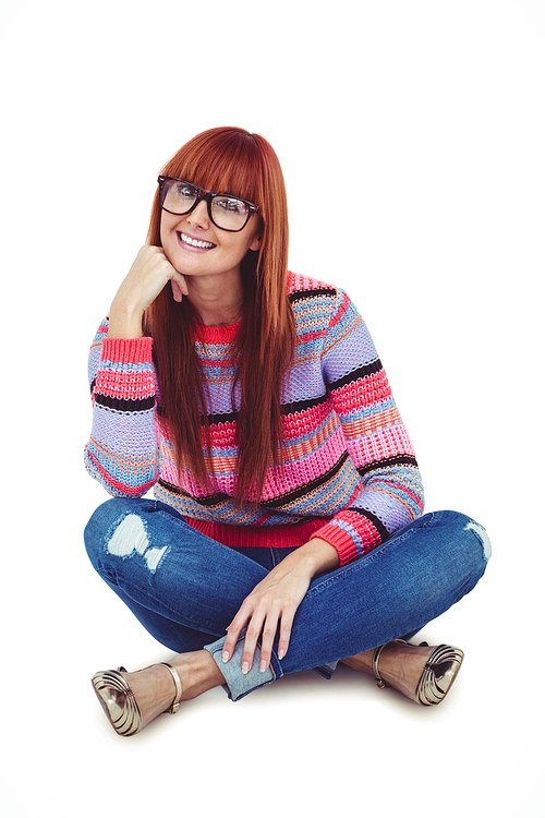Smiling hipster woman sitting on the floor against white background