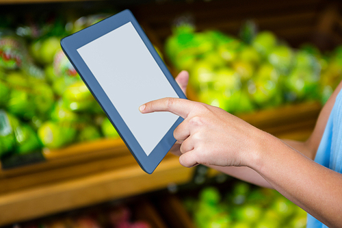 Womans hand using tablet in grocery shop