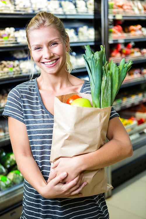 Beautiful woman standing with grocery bag in supermarket