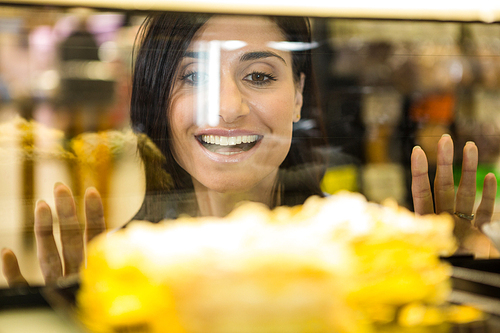 Pretty smiling woman choosing her dessert in supermarket