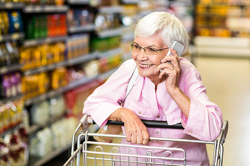 Smiling senior woman on phone in supermarket