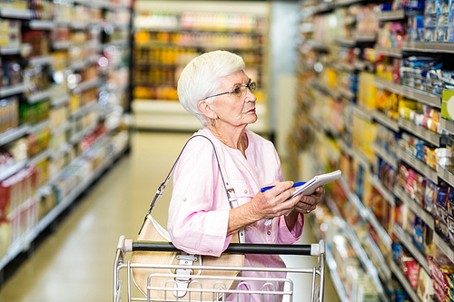 Senior woman with shopping list in supermarket