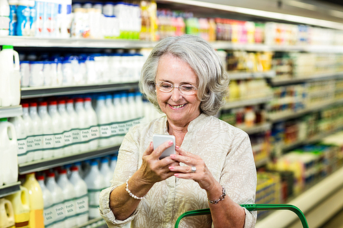 Smiling senior woman using smartphone at the supermarket