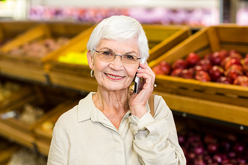 Old woman having a phone call in supermarket