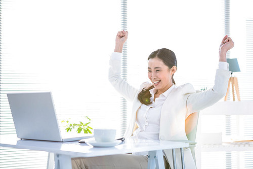 Businesswoman rejoicing with arms outstretched in office