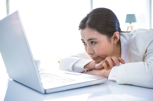 Serious woman leaning her chin on her hands in office