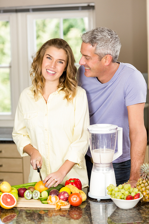 Smiling couple preparing healthy smoothie in the kitchen