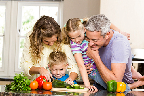 Happy family slicing vegetables in the kitchen