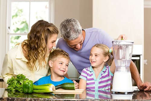 Happy family preparing healthy smoothie in the kitchen