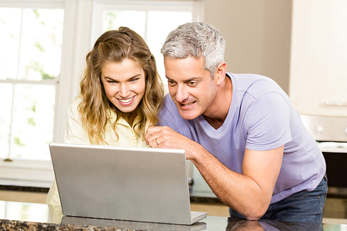 Happy couple using laptop together in the kitchen