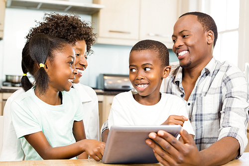 Happy family using tablet in kitchen at home